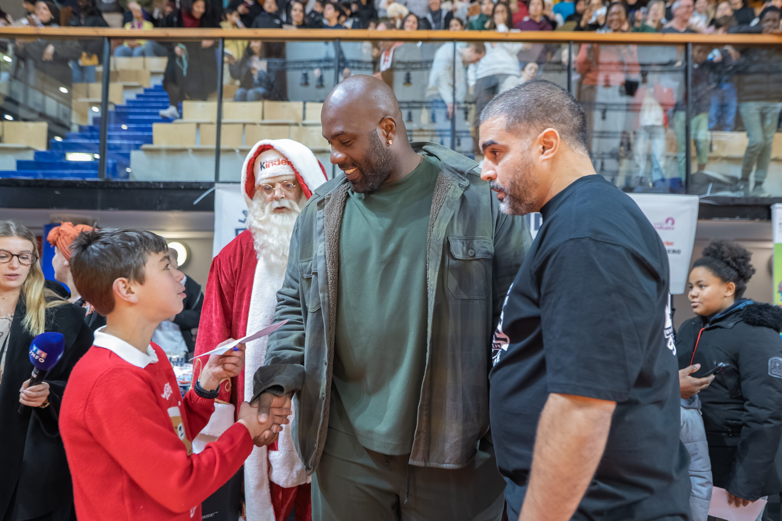Teddy Riner remet un diplôme à un participant de la plus grande dictée du monde au Dojo de Paris.